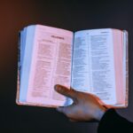 A person holds an open Bible with Proverbs highlighted, bathed in warm light.